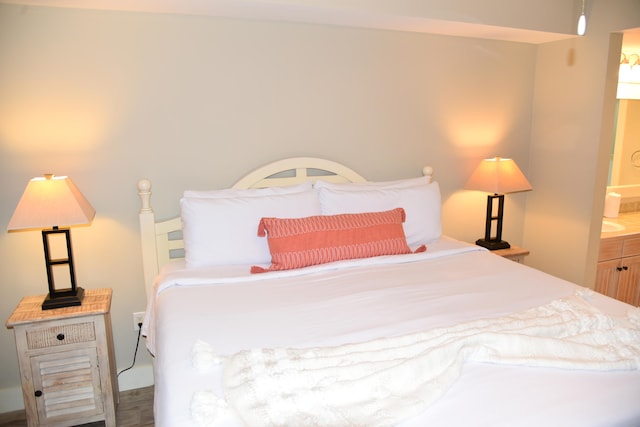 bedroom with hardwood / wood-style flooring and ensuite bath