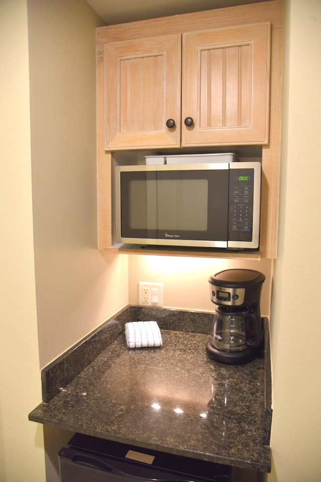 room details featuring dark stone countertops and light brown cabinetry