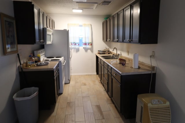 kitchen with a textured ceiling, white appliances, light hardwood / wood-style flooring, and sink