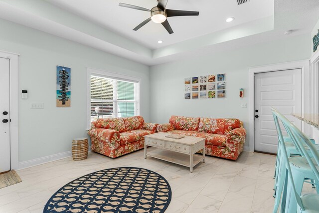 living room featuring a tray ceiling and ceiling fan