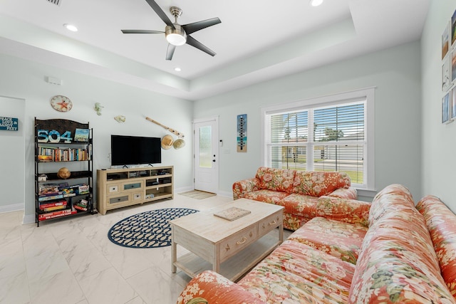 living room featuring a tray ceiling and ceiling fan