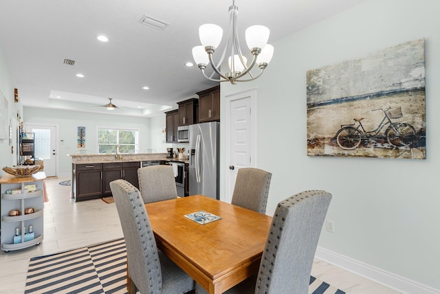 dining room with ceiling fan with notable chandelier and sink