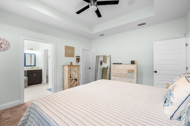 carpeted bedroom featuring connected bathroom, a tray ceiling, ceiling fan, and sink