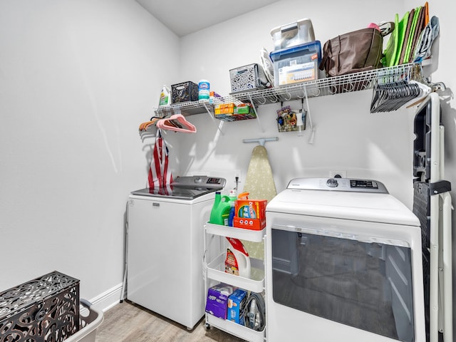 clothes washing area with separate washer and dryer and light hardwood / wood-style flooring