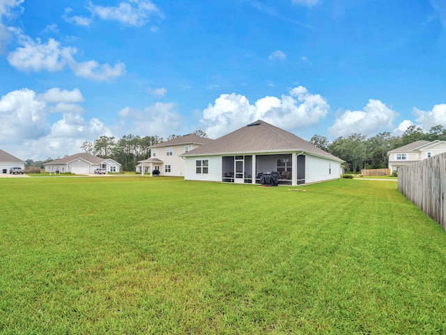 rear view of house with a yard and a sunroom