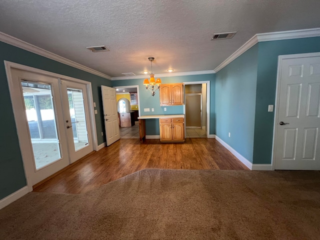 kitchen featuring light hardwood / wood-style floors, ornamental molding, a textured ceiling, and hanging light fixtures