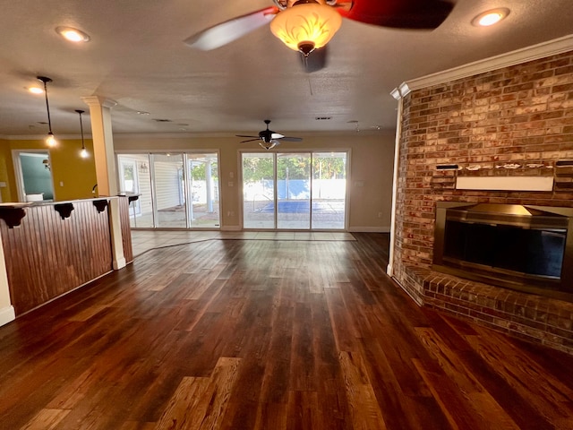 unfurnished living room featuring a textured ceiling, ceiling fan, ornamental molding, and dark wood-type flooring