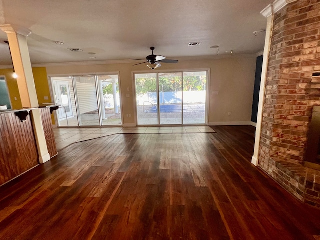 unfurnished living room with dark wood-type flooring, ceiling fan, ornamental molding, a textured ceiling, and ornate columns