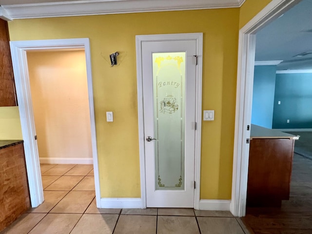 doorway featuring ornamental molding and light tile patterned floors