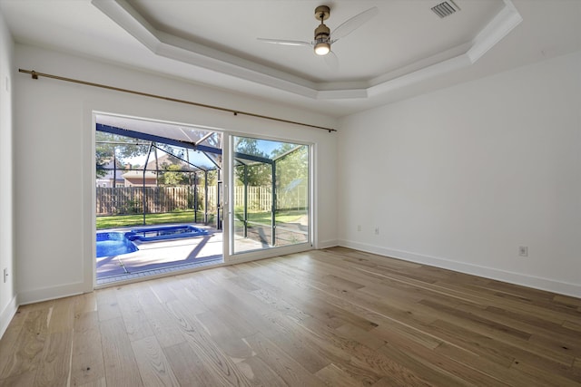 unfurnished room featuring hardwood / wood-style flooring, ceiling fan, and a tray ceiling