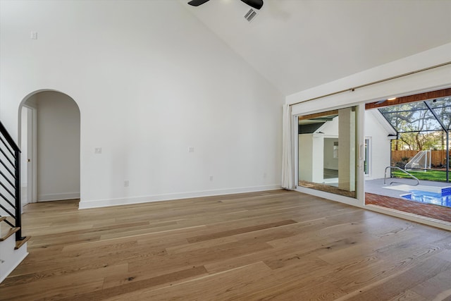 empty room with ceiling fan, light hardwood / wood-style flooring, and high vaulted ceiling