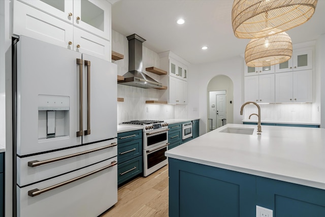 kitchen featuring white cabinets, wall chimney exhaust hood, high end appliances, and sink