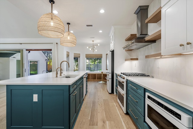 kitchen featuring white cabinetry, sink, wall chimney range hood, appliances with stainless steel finishes, and light wood-type flooring