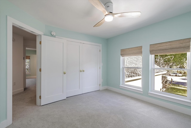 unfurnished bedroom with ceiling fan, light carpet, and a closet