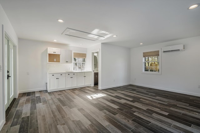 unfurnished living room with a wealth of natural light, dark hardwood / wood-style flooring, and a wall mounted air conditioner