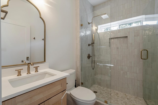 bathroom featuring vanity, toilet, and a shower with shower door