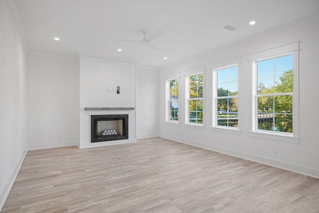 unfurnished living room with crown molding, a large fireplace, ceiling fan, and light hardwood / wood-style floors