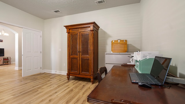 office with light wood-type flooring and a textured ceiling