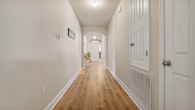 hall featuring light hardwood / wood-style floors and a textured ceiling