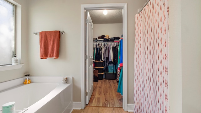 bathroom with wood-type flooring, a textured ceiling, and a bathing tub