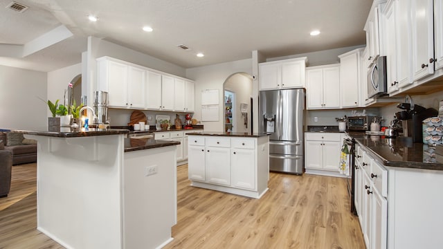 kitchen with a center island, white cabinets, light wood-type flooring, a textured ceiling, and appliances with stainless steel finishes