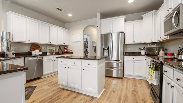 kitchen with white cabinets, a kitchen island, light wood-type flooring, and appliances with stainless steel finishes