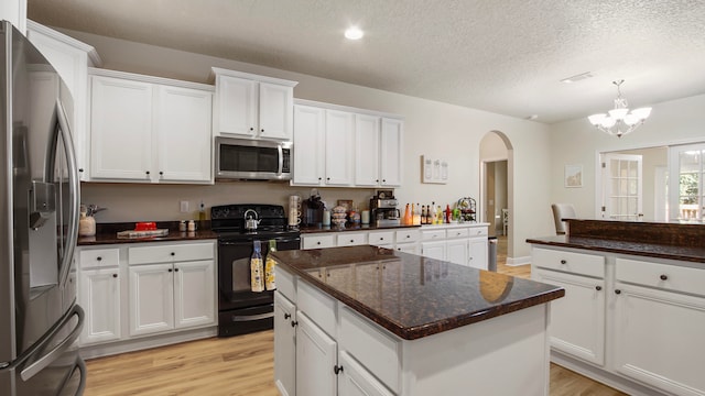 kitchen with white cabinets, a kitchen island, stainless steel appliances, and a textured ceiling