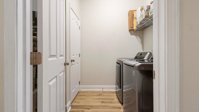 laundry area with separate washer and dryer and light hardwood / wood-style flooring