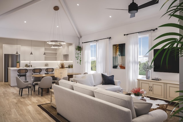 living room featuring lofted ceiling with beams, ceiling fan with notable chandelier, and light wood-type flooring