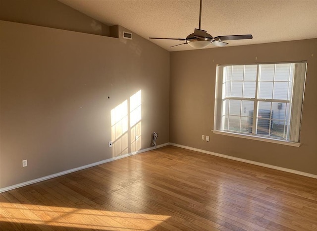 spare room featuring lofted ceiling, a textured ceiling, wood-type flooring, and ceiling fan