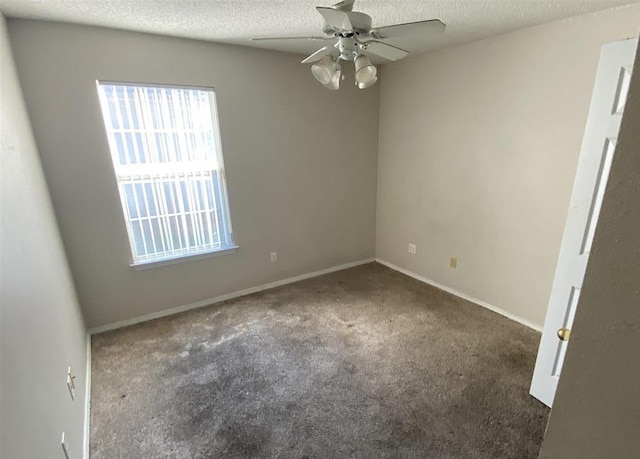 unfurnished room with ceiling fan, dark carpet, and a textured ceiling