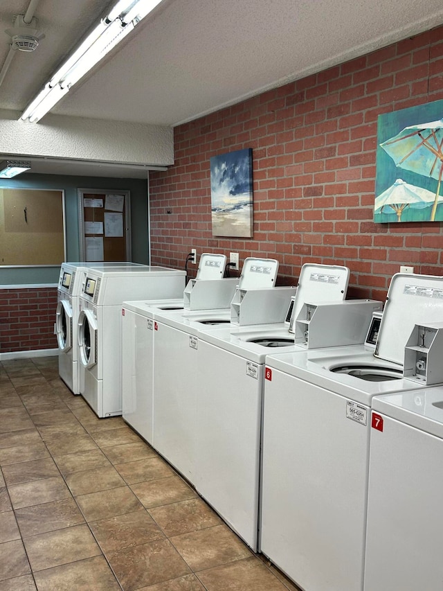 clothes washing area featuring brick wall, a textured ceiling, and independent washer and dryer