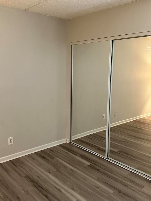 unfurnished bedroom featuring a closet and dark hardwood / wood-style flooring