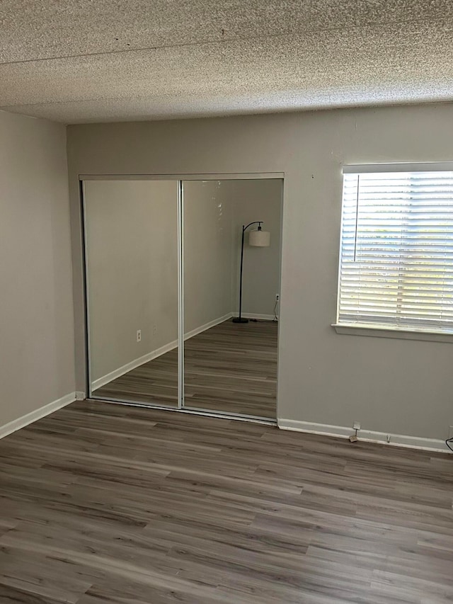 unfurnished bedroom with a textured ceiling, dark hardwood / wood-style floors, and a closet