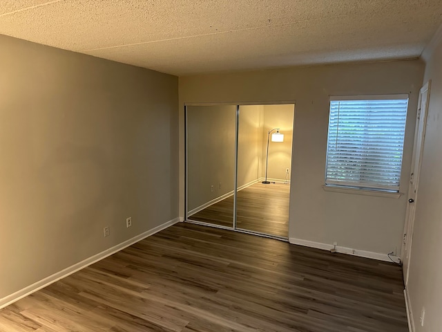 unfurnished bedroom featuring a closet, dark wood-type flooring, and a textured ceiling