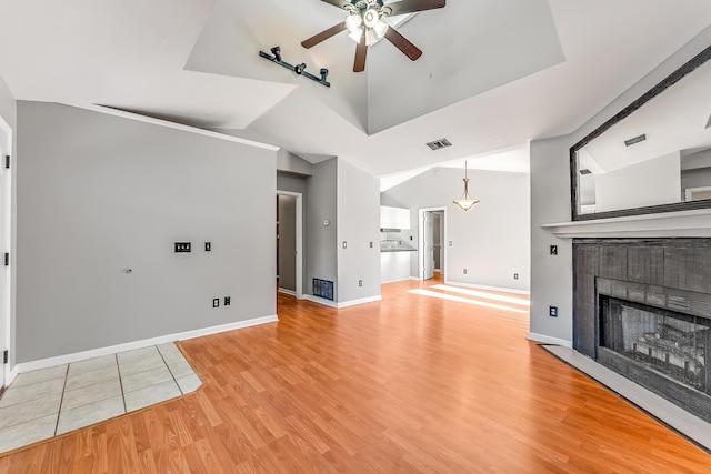 unfurnished living room featuring ceiling fan, light hardwood / wood-style floors, lofted ceiling, and a tile fireplace