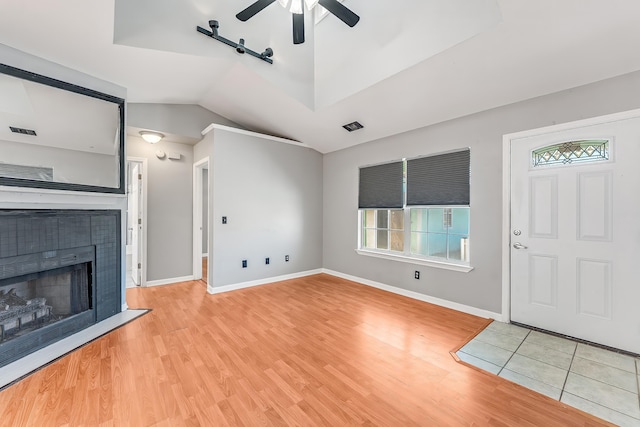 unfurnished living room featuring a tiled fireplace, ceiling fan, light hardwood / wood-style flooring, and lofted ceiling