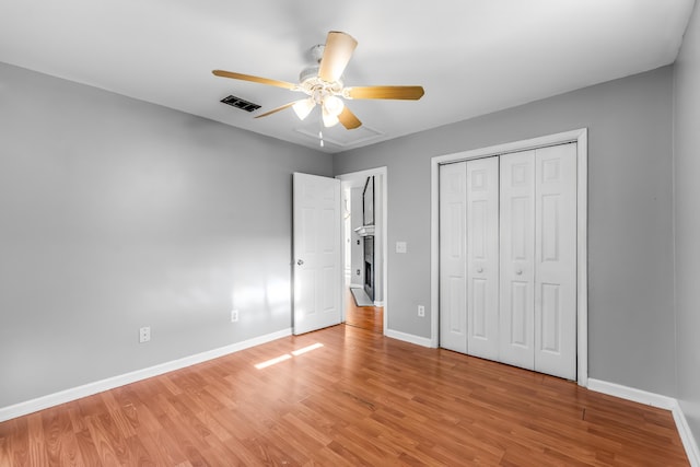 unfurnished bedroom with ceiling fan, a closet, and hardwood / wood-style flooring