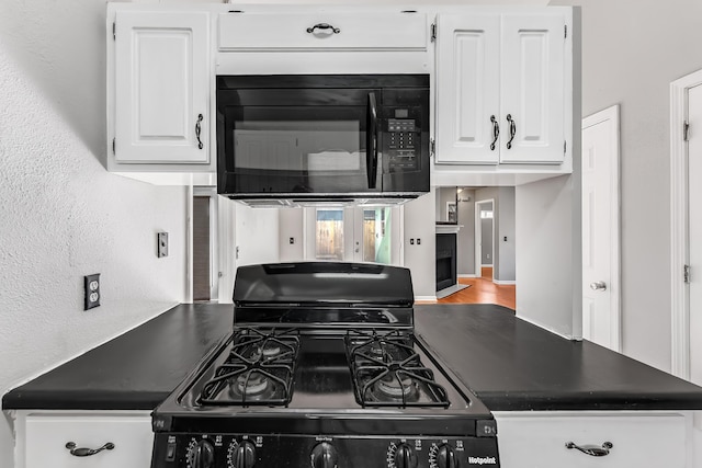 kitchen featuring black appliances, wood-type flooring, and white cabinetry