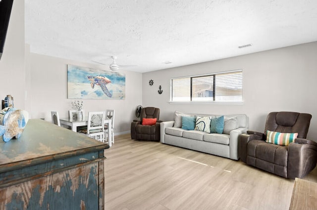 living room featuring hardwood / wood-style floors, a textured ceiling, and ceiling fan