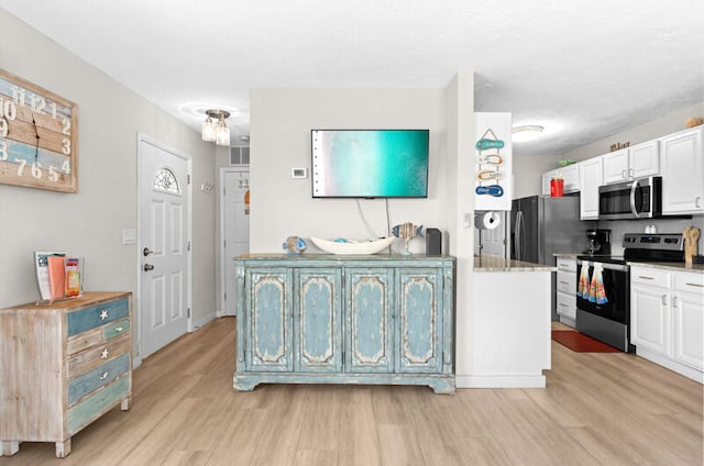 kitchen featuring white cabinets, stainless steel appliances, and light hardwood / wood-style flooring