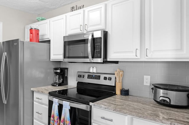 kitchen with white cabinetry, light stone counters, a textured ceiling, decorative backsplash, and appliances with stainless steel finishes