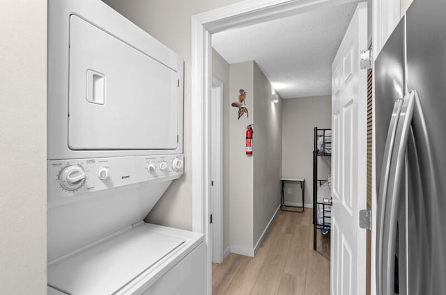 laundry area with light hardwood / wood-style floors and stacked washer and clothes dryer