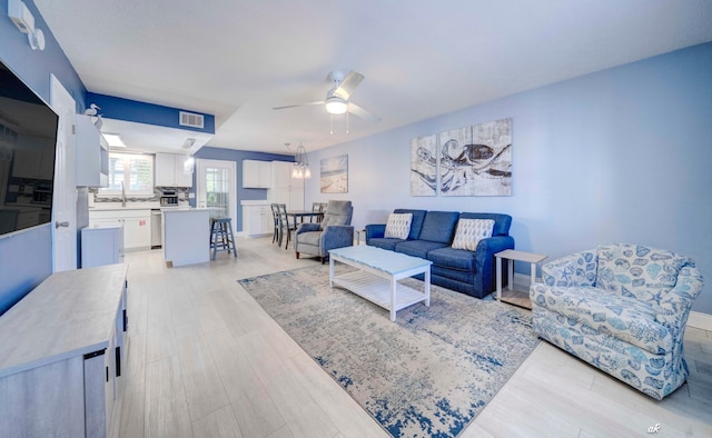 living room with light hardwood / wood-style floors, ceiling fan, and sink