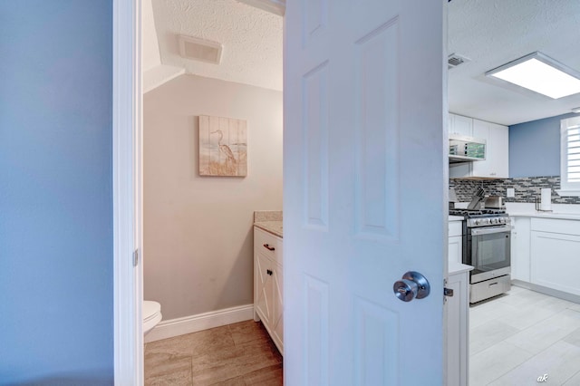 bathroom featuring decorative backsplash, vanity, a textured ceiling, and toilet