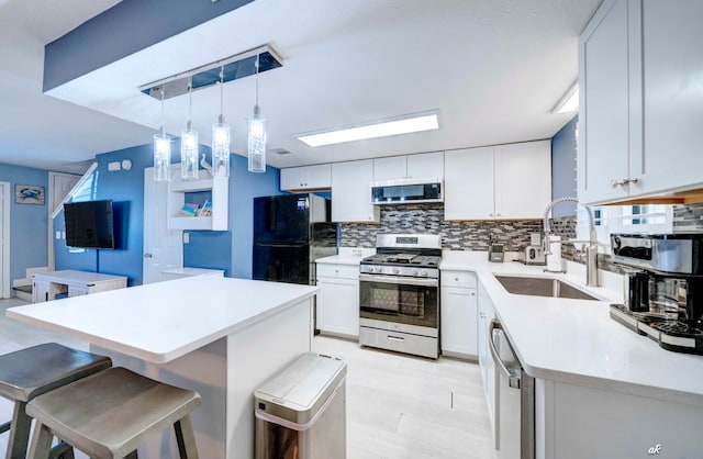 kitchen with a breakfast bar, white cabinetry, sink, and appliances with stainless steel finishes