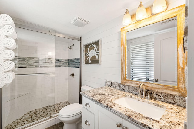 bathroom with vanity, toilet, a shower with shower door, and wooden walls