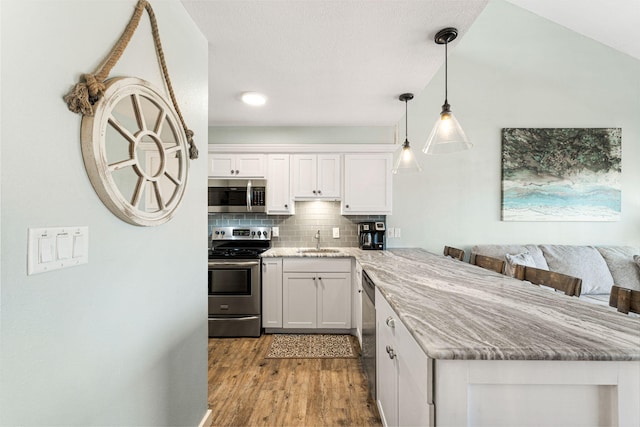 kitchen with backsplash, white cabinets, light wood-type flooring, and appliances with stainless steel finishes