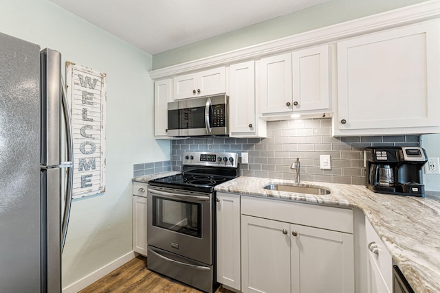 kitchen featuring hardwood / wood-style floors, sink, light stone counters, white cabinetry, and stainless steel appliances