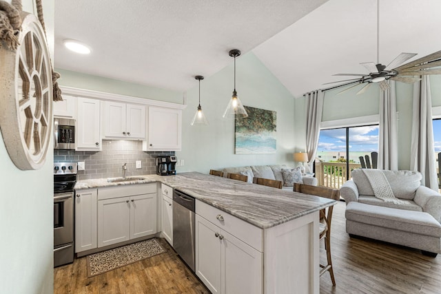 kitchen with a kitchen breakfast bar, kitchen peninsula, white cabinetry, and stainless steel appliances